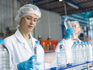 picture of a lady inspecting water bottles on a production line